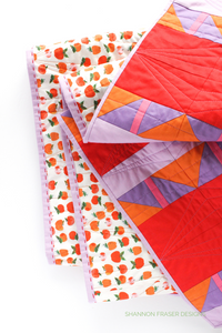 Big stitch binding detail plus the apples print by Heather Ross on the back of the Shattered Star quilt featuring Ruby & Bee solids in red, purple, orange, pink and lilac. Shannon Fraser Designs #modernquilt