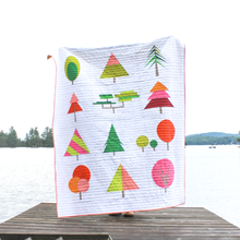 Load image into Gallery viewer, Colorful tree-patterned quilt on a wooden dock with a lake and trees in the background