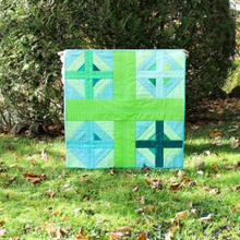 Load image into Gallery viewer, Green and blue quilt with geometric pattern held up outdoors on grass