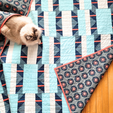 Load image into Gallery viewer, Cat lying on a geometric-patterned quilt with a wooden floor underneath